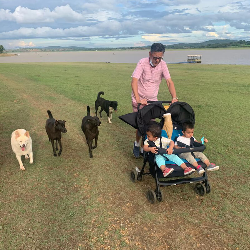 Waterwoods founder taking a stroll with twin daughters in a stroller followed by pet dogs at Kabini