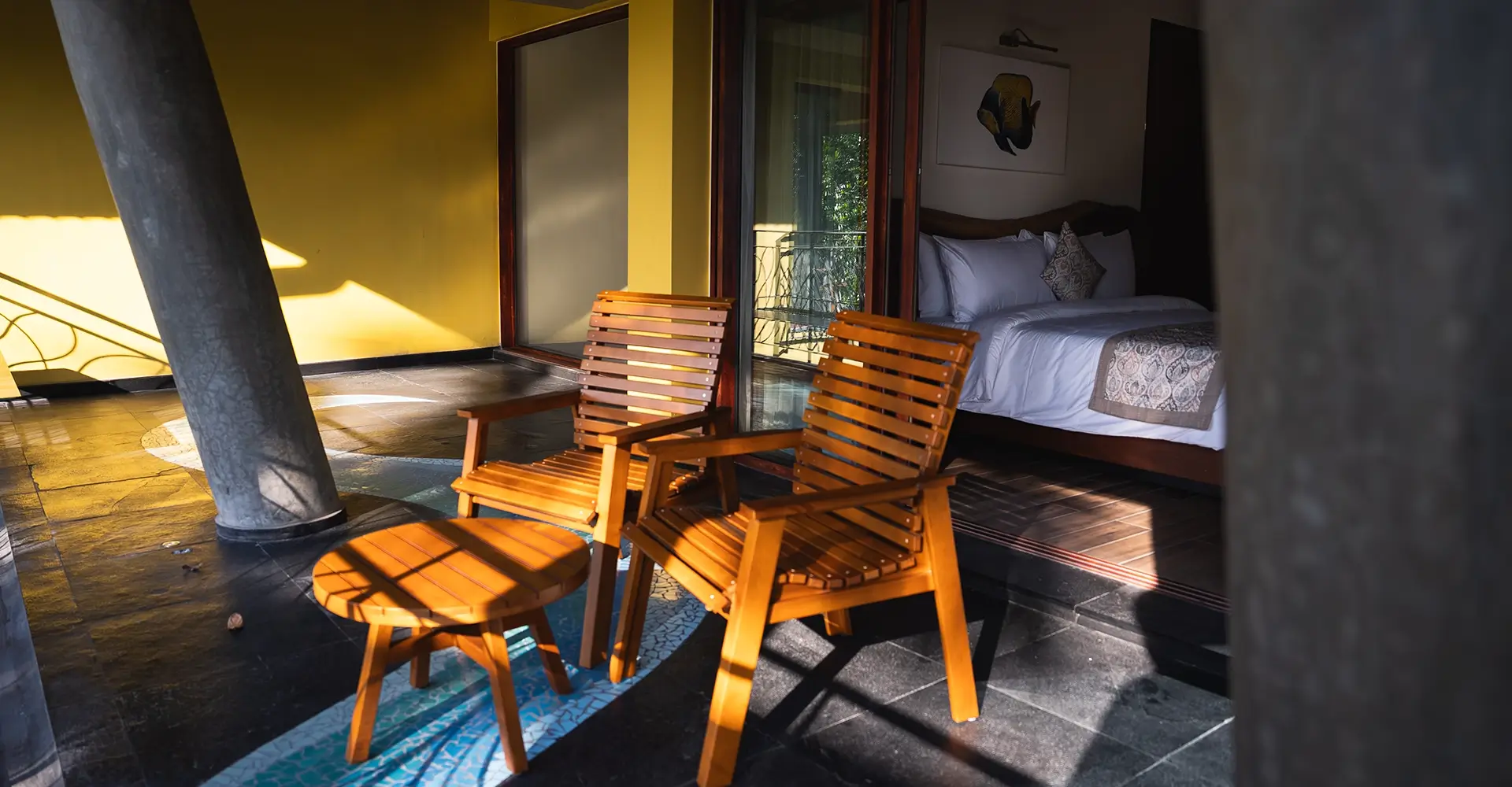 Outdoor deck seating at Waterwoods Havelock villa with wooden chairs and sunlight filtering through coconut trees.