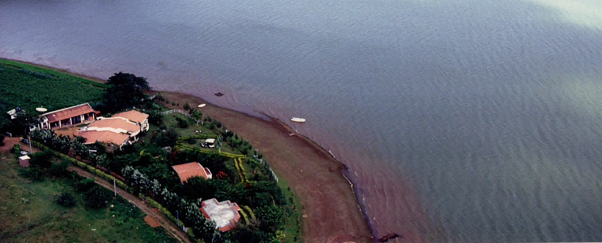Aerial view of Waterwoods Kabini Lodge on the banks of the Kabini River, captured in 1999, showcasing the resort’s origins amidst lush greenery
