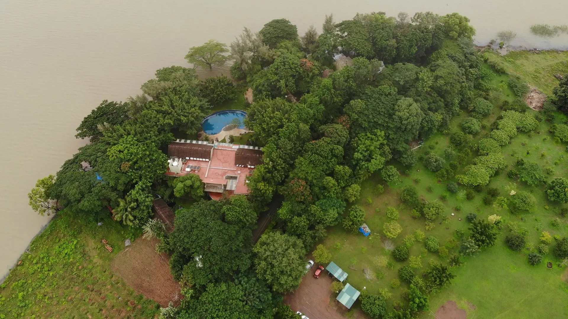 Aerial view of Waterwoods Kabini resort surrounded by greenery with pool beside the river