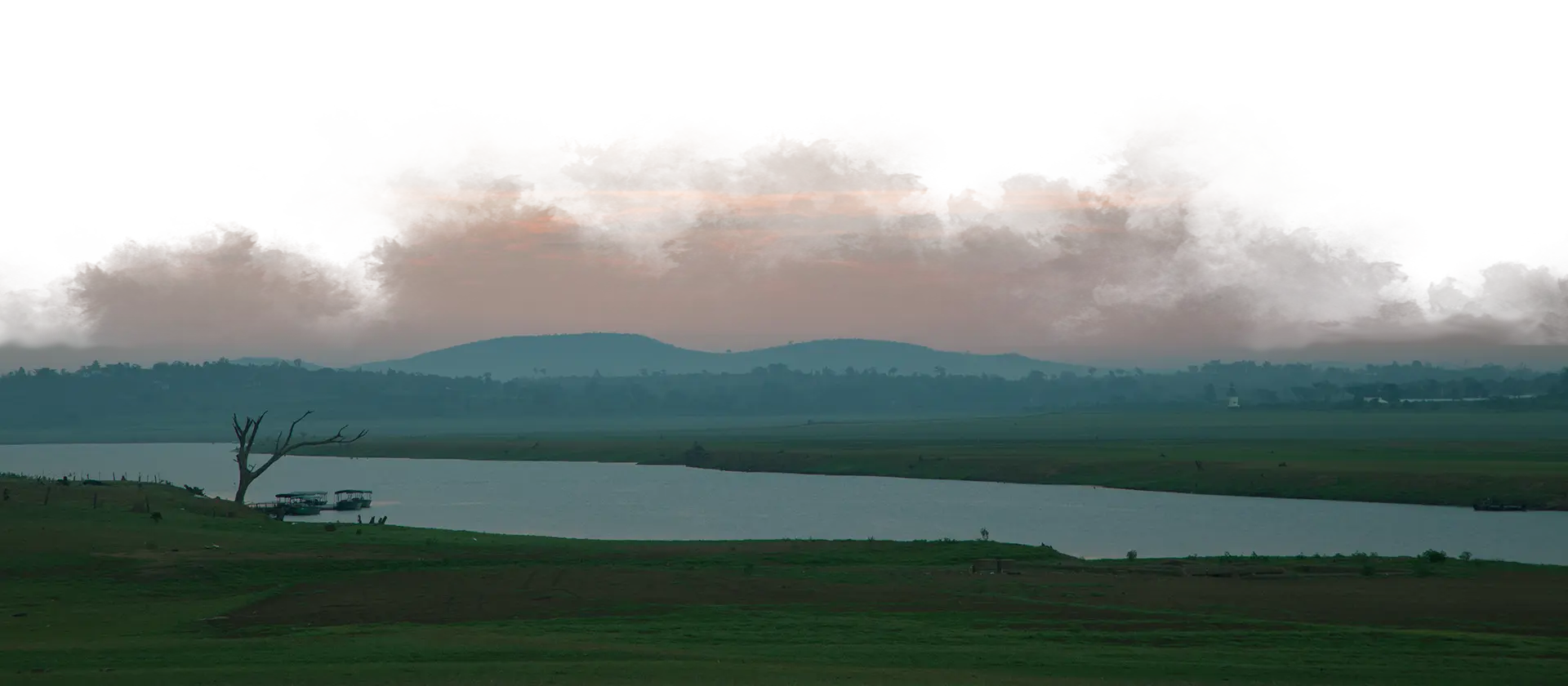 Serene view of Kabini backwaters at sunset with distant hills and tranquil waters near Waterwoods Lodge.