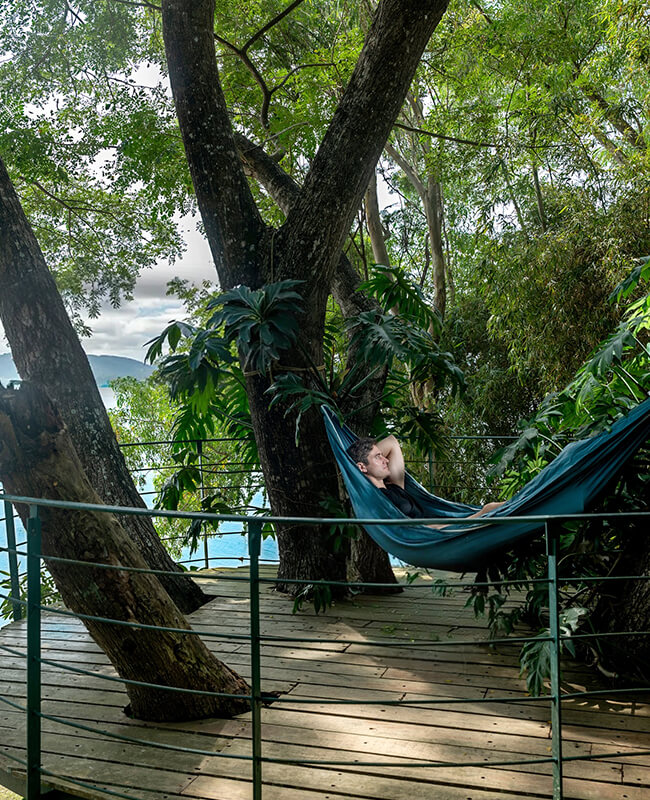Guest relaxing on a hammock overlooking the backwaters at Waterwoods Kabini