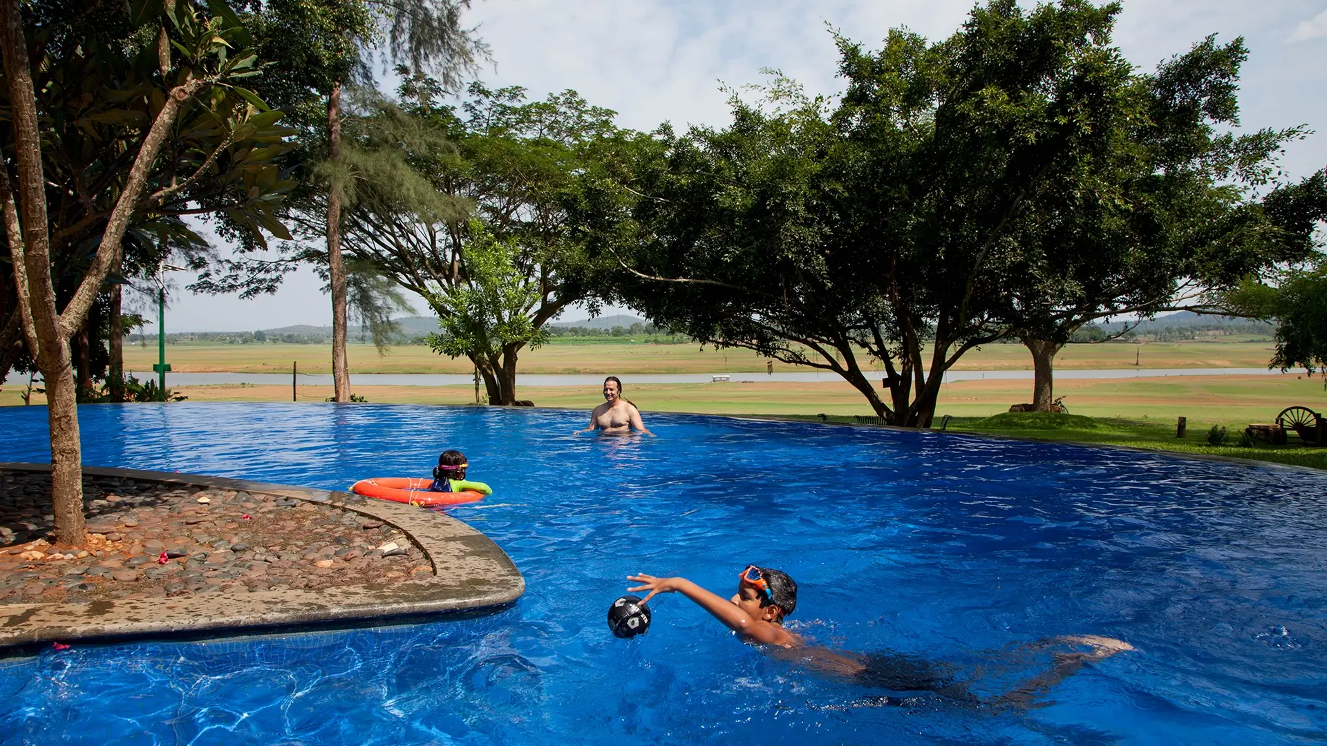 Guests enjoying infinity pool overlooking Kabini backwaters at Waterwoods Lodge