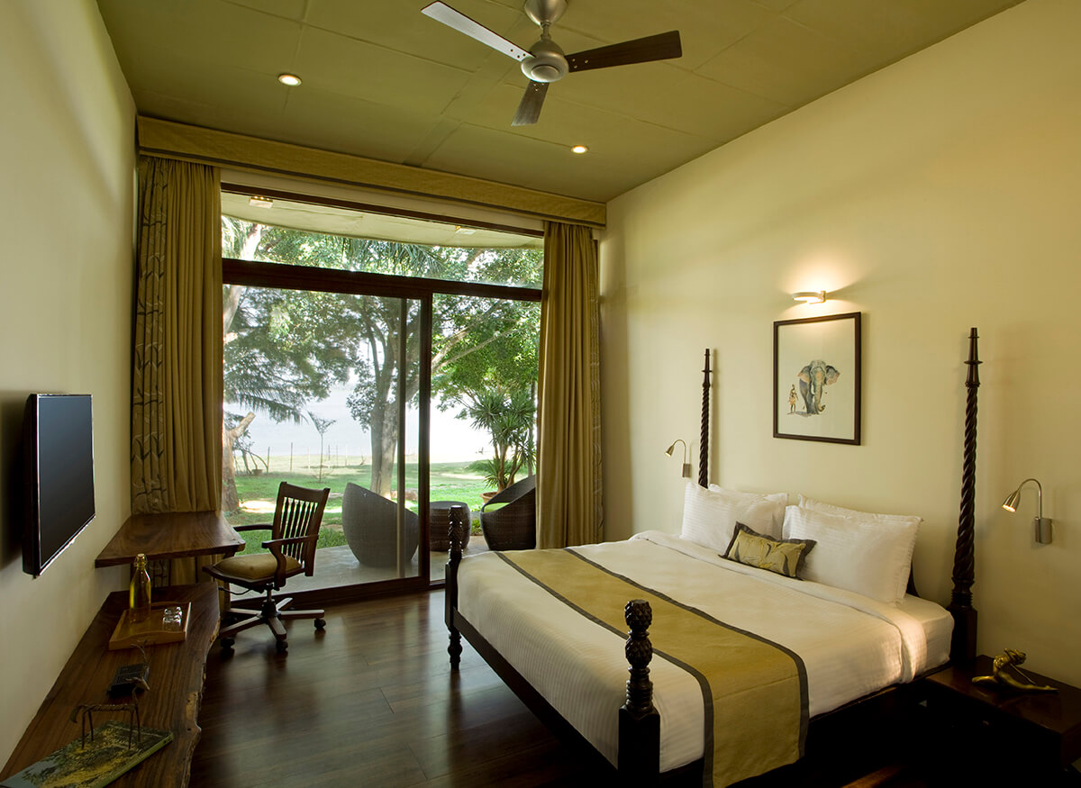 Spacious King Room at Waterwoods Kabini with wooden flooring, large bed, and private deck overlooking nature.