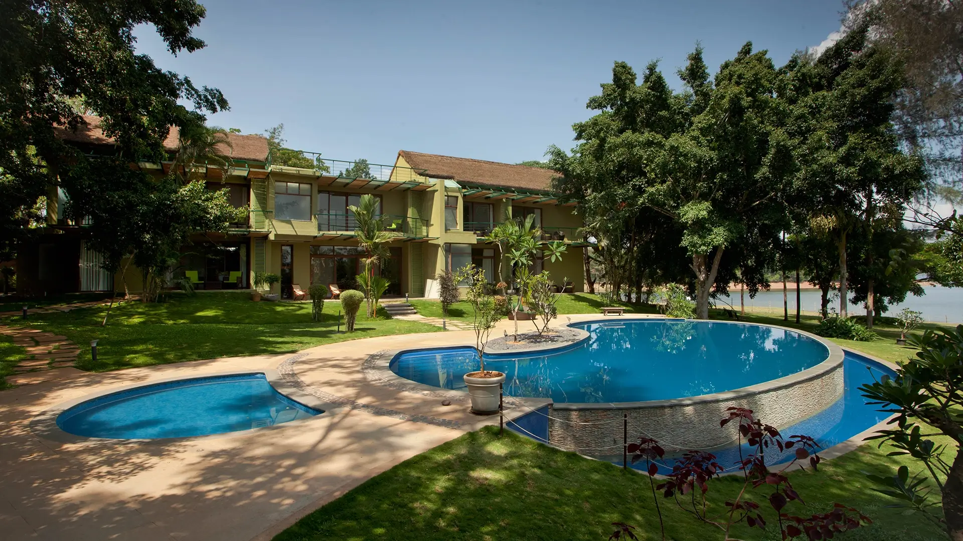 Daytime view of Waterwoods Kabini resort with swimming pool and garden surroundings