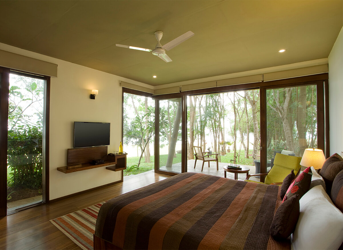 Superior King Room at Waterwoods Kabini featuring glass walls with backwater views and elegant interiors.