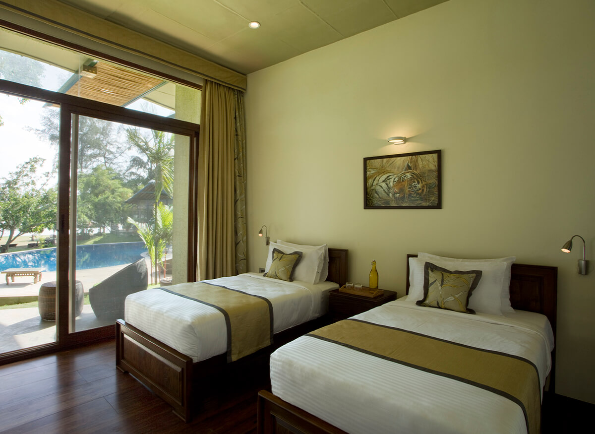 Twin Room at Waterwoods Kabini with two single beds, pool view, and bright natural lighting.