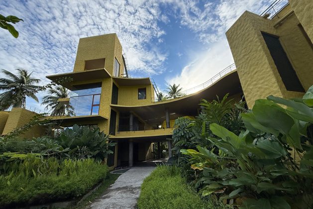 Contemporary resort architecture at Waterwoods Havelock with bold yellow structures and surrounding coconut trees.
