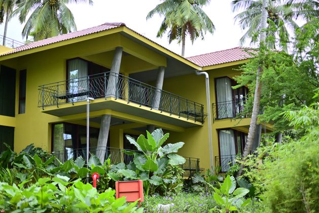 Twin villa exteriors at Waterwoods Havelock surrounded by large tropical leaves and coconut trees.